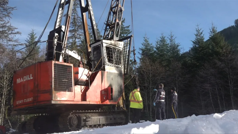 RCMP and fire investigators examine burned logging equipment along a remote Cowichan Lake road. Image via CHEK News