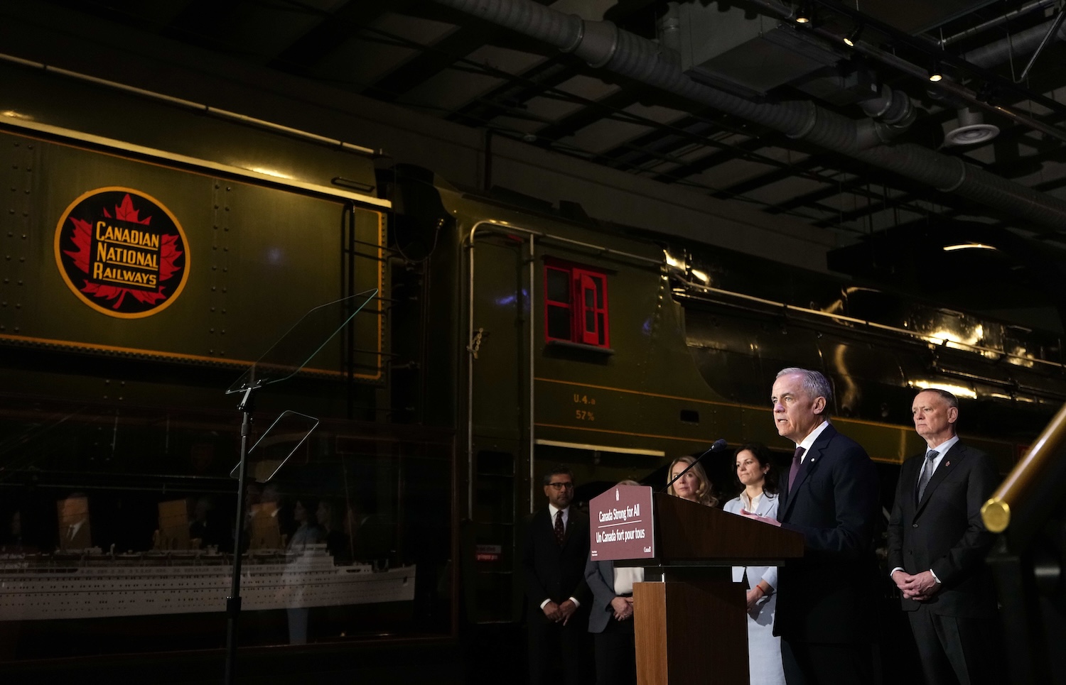 Prime Minister Mark Carney speaks from a lectern beside a Canadian National Railways locomotive at the Canada Science and Technology Museum, during an announcement on the Canada Strong Fund, Canada's first sovereign wealth fund in Ottawa on Monday, April 27, 2026. THE CANADIAN PRESS/Justin Tang